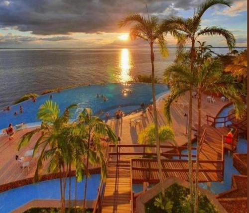 马瑙斯Hotel Tropical Executive Flat 918的毗邻大海的大型游泳池,种植了棕榈树