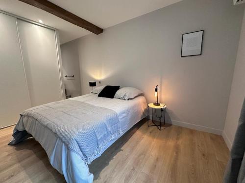 利勒达博La maison de Mounette的一间卧室配有一张床和一盏灯,铺有木地板