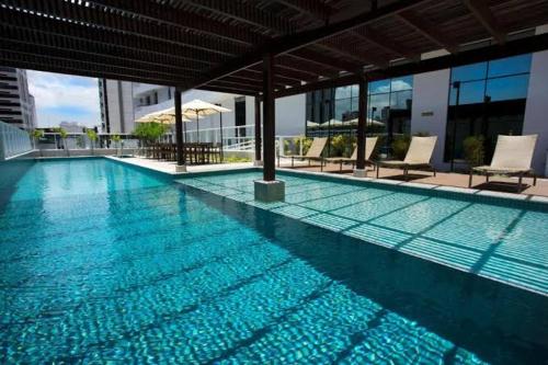 萨尔瓦多Apartamento Mondial Salvador的大楼内带椅子的大型游泳池