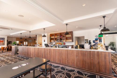 沃加沃加Sportsmens Club Hotel的餐厅内的酒吧配有桌椅