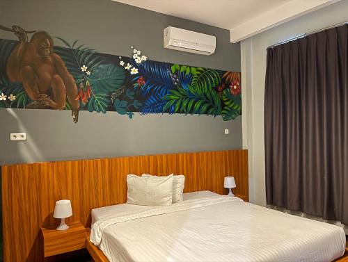 SintangLadja Hotel Sintang的卧室配有一张床,墙上挂有绘画作品