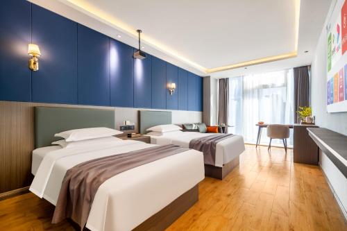 太原素柏云酒店（晋阳街店）的两张位于酒店客房的床,拥有蓝色的墙壁