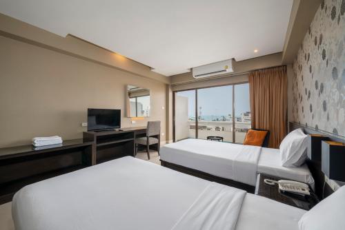 芭堤雅市中心芭提雅迎宾广场酒店的酒店客房配有两张床和一张书桌