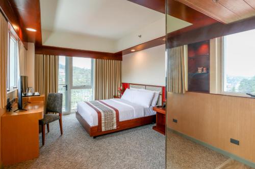 碧瑶Sotogrande Hotel Baguio的酒店客房设有一张床、一张书桌和窗户。