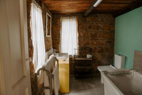 Curryʼs PostAudley End Farm的一间带两个水槽和石墙的浴室
