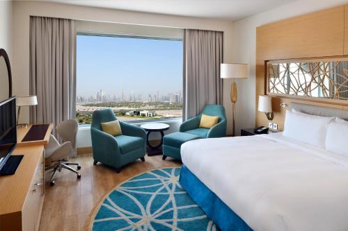迪拜Marriott Hotel Al Jaddaf, Dubai的酒店客房设有床、椅子和大窗户。