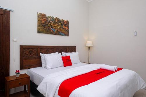 KlatenRedDoorz Syariah near Stasiun Klaten的卧室配有一张大白色床和红色毯子