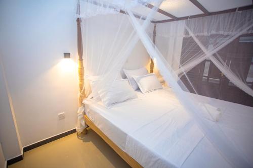 哈巴拉杜瓦Kusumvillahabarduwa的卧室配有带蚊帐的白色床