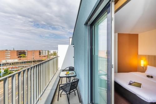 巴塞尔巴塞尔班霍夫宜必思酒店的客房设有阳台、一张床和一张书桌