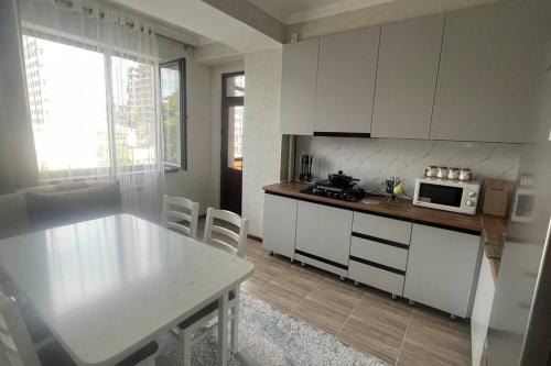 比什凯克Apartament Manasa的厨房配有白色橱柜、桌子和微波炉