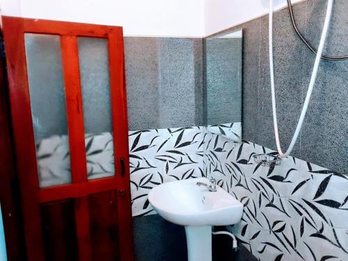 康提Black And White Kandy Guest House 01的浴室设有白色水槽和黑白壁纸。