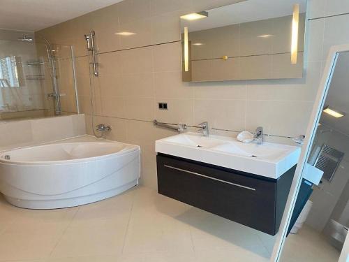 布拉索夫Penthouse Silver Mountain, Duplex 3 camere - 250 mp luxury garden - Poiana Brasov的带浴缸和盥洗盆的浴室