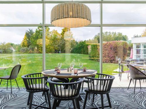 圣皮耶尔勒迪佩尔赖瑟纳特高尔夫绿色公园诺富特酒店的配有大窗户的客房内的桌椅