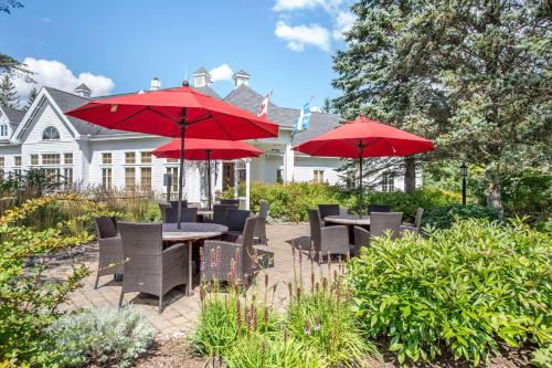 蒙特朗布朗Hilton Grand Vacations Club Tremblant Canada的一个带桌椅和红伞的庭院