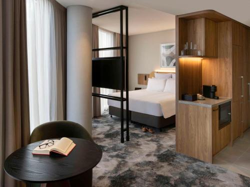 彭里斯Pullman Sydney Penrith的酒店客房设有一张双层床和一张桌子,并备有书籍