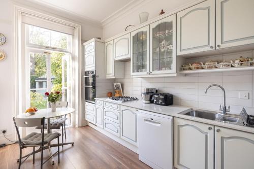 伦敦Veeve - Courtside Charms的厨房配有白色橱柜、水槽和桌子
