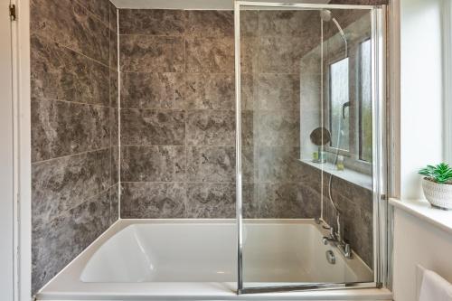 Loughton3 Bedroom Home in Central Milton Keynes的浴室内设有一个带玻璃淋浴间的浴缸