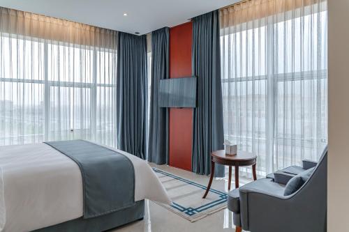 塞拉莱Salalah International Hotel的一间卧室配有一张床、一把椅子和窗户。