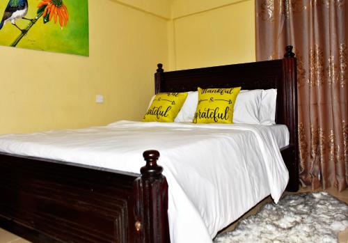 Kiambuone bedroom in oj town ruiru的一张带白色床单和黄色枕头的床