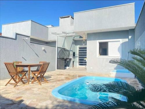 瓜拉图巴Casa com piscina duas quadras da praia的一个带桌椅的庭院和一个游泳池
