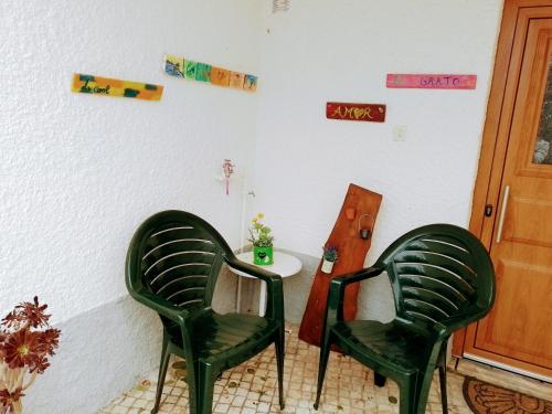 戈韦阿Casa dos Quatro Irmãos的一张桌子的房间里设有两张绿色椅子