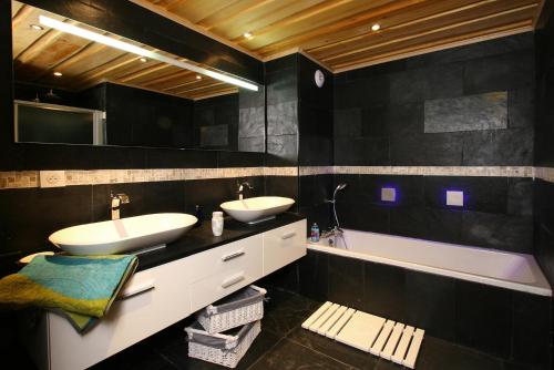 莱德萨阿尔卑斯Odalys Chalet Leslie Alpen 2的黑色浴室设有两个盥洗盆和浴缸。