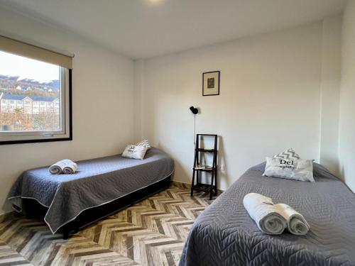 乌斯怀亚Disfruta la vista del Canal de Beagle! Departamento tranquilo rodeado de Árboles y montañas的一间卧室设有两张床和窗户。