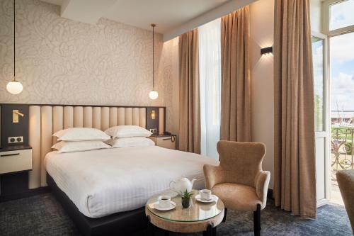 波亚克Best Western Premier Hotel des Vignes et des Anges的配有一张床和一把椅子的酒店客房