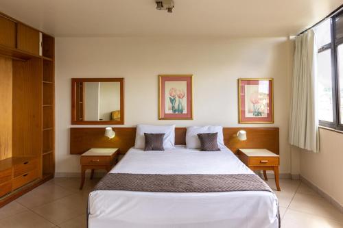 乌贝拉巴UBERABA APART HOTEL的卧室配有一张带两张桌子的大型白色床