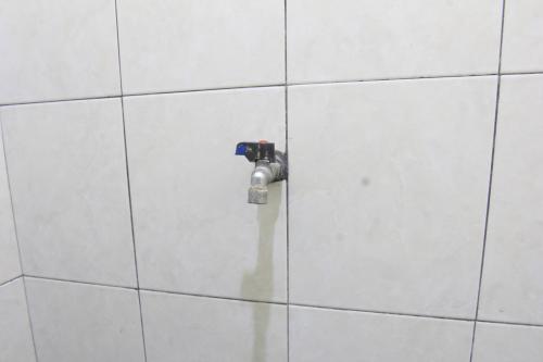 丹戎OYO Life 93157 Kos Kaloka的白色瓷砖墙上的淋浴阀