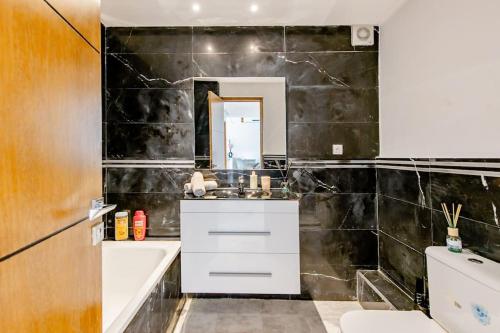 丹吉尔Élégant appart tanger boulevard的浴室设有黑色瓷砖墙和水槽。
