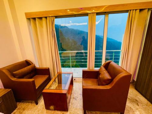 西姆拉Hotel candlewood Shimla的客厅配有两把椅子和大窗户