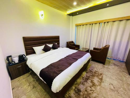西姆拉Hotel candlewood Shimla的一间卧室配有一张大床和两把椅子