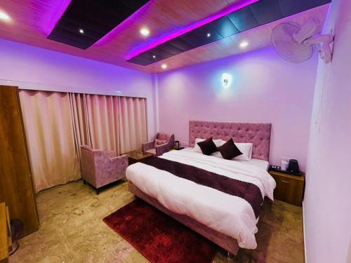 西姆拉Hotel candlewood Shimla的一间卧室配有一张大床和紫色照明