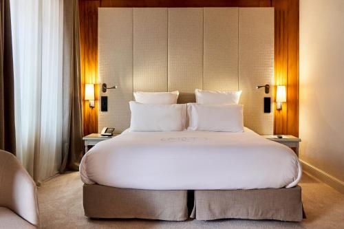 科尔马Relais & Châteaux La Maison Des Têtes的卧室配有带白色枕头的大床