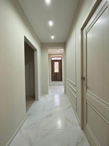 久姆里Lidiani Guest House的一条空的走廊,有门,有白色的瓷砖地板