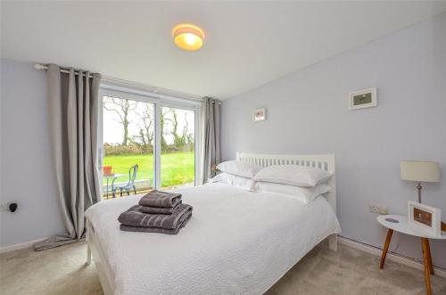 德维兰Gwyllt Cottages的卧室设有白色的床和大窗户