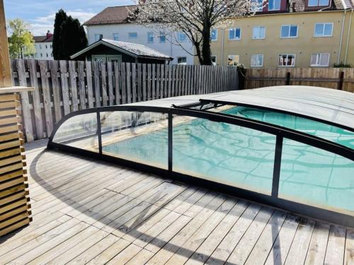 卡尔马Central villa med extra allt. Pool, Bastu, Utekök的甲板上设有玻璃围墙的游泳池