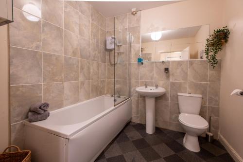 卡迪夫13 Victoria Road Apartment的浴室配有卫生间、盥洗盆和浴缸。