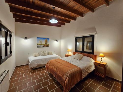 圣安东尼奥德阿雷科Posada del Atelier的一间带两张床的卧室,位于木天花板的房间
