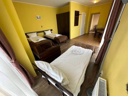利沃夫Готель Цісар的一间设有两张床的客房,位于拥有黄色墙壁的房间