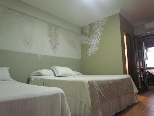 沙帕达-杜斯吉马朗伊斯望厦别墅吉马良斯旅馆的卧室配有2张床,墙上铺有白色床单和棕榈叶。