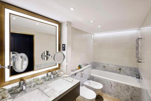 布达佩斯布达佩斯希尔顿酒店的浴室配有盥洗盆、卫生间和浴缸。