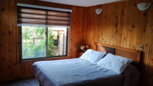 安加罗阿Cabaña Uka Moana的一间卧室设有一张大床和大窗户