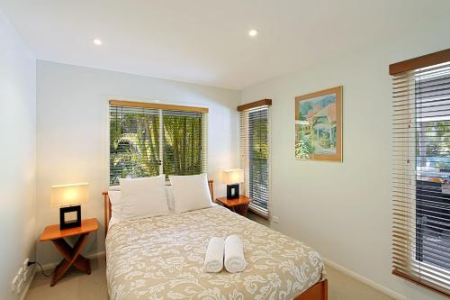 EwingsdaleA Perfect Stay - Abode at Byron的一间卧室配有一张带两盏灯的床和两扇窗户。