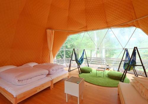 Urugiglampark Morinoyado Nagano的一间设有两张床的房间和帐篷内的秋千