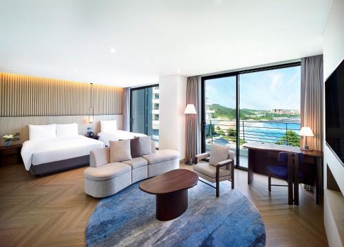 西归浦市Parnas Hotel Jeju的酒店客房配有床、沙发和桌子。