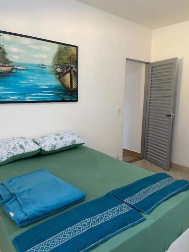 PalmasPousada Luciana Dias的卧室配有一张绿色的床,墙上挂着一幅画