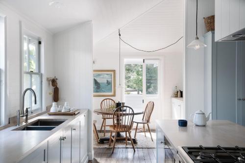 布伦瑞克黑兹RiverFish的厨房配有白色橱柜和桌椅