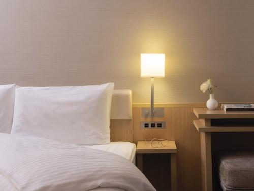 京都三井花园饭店 京都新町别邸的一间卧室配有一张床和一张桌子上的台灯